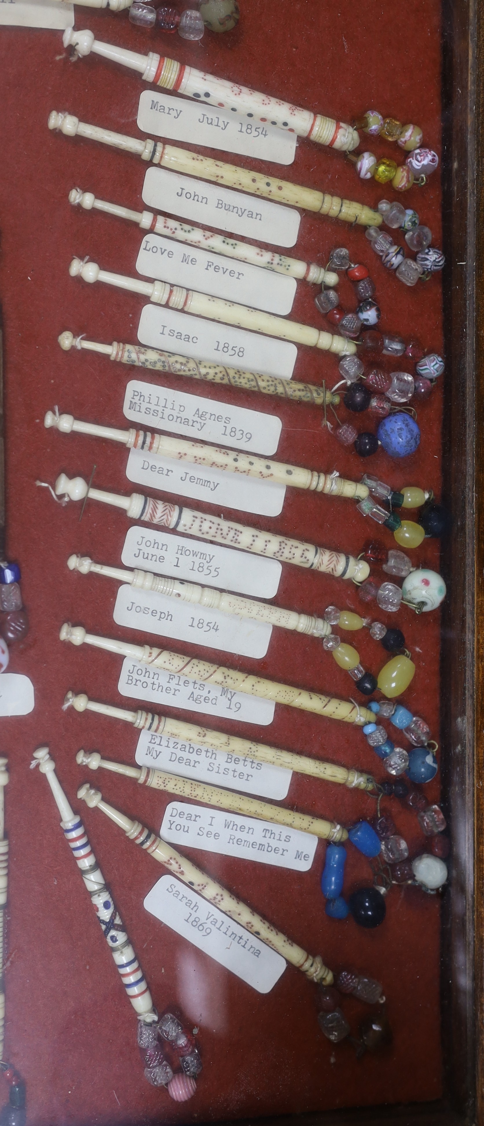 A cased collection of 19th century inscribed bone and glass bead lace bobbins, some dated and named